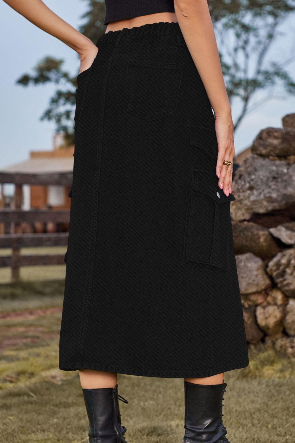 Black denim midi skirt with cargo pockets and a slit, styled with boots.