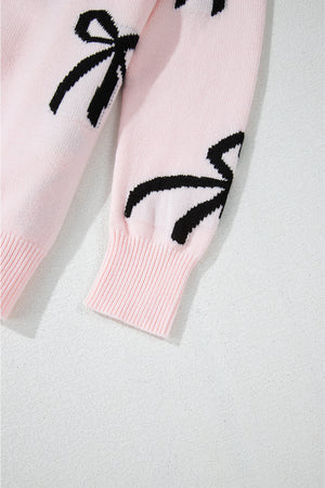 Blush pink knit crewneck sweater with black bow motifs and ribbed cuffs.
