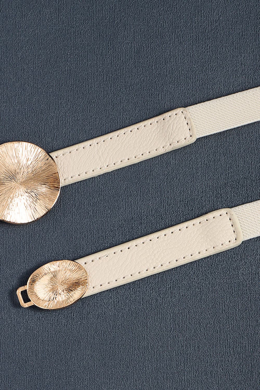 Ivory elastic belt with textured gold disc detail and faux leather trim.
