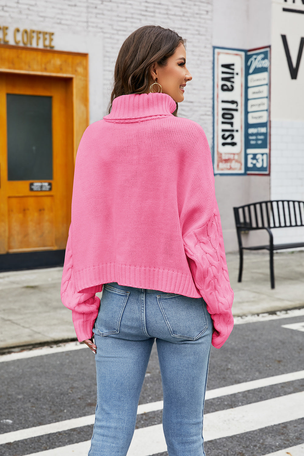 Cropped cable knit turtleneck sweater in hot pink with a high neck and cuffed sleeves.