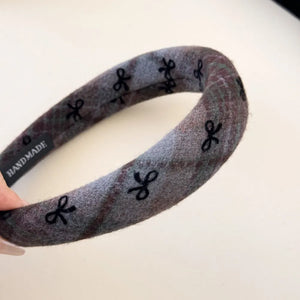 Embroidered plaid padded headband in dark gray with black bow pattern.