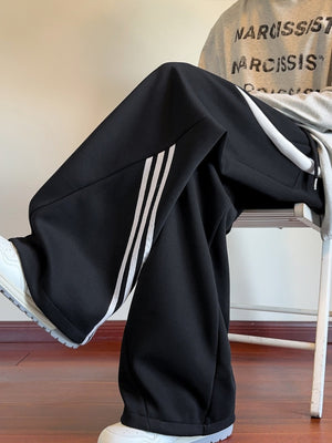 Black wide-leg sweatpants with white stripe detail on the side.