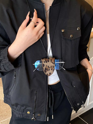 Leopard print glasses case on a cord, worn with a black jacket and white top.