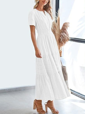 White V-neck tiered maxi dress with short sleeves and smocked waist, styled with strappy heels.