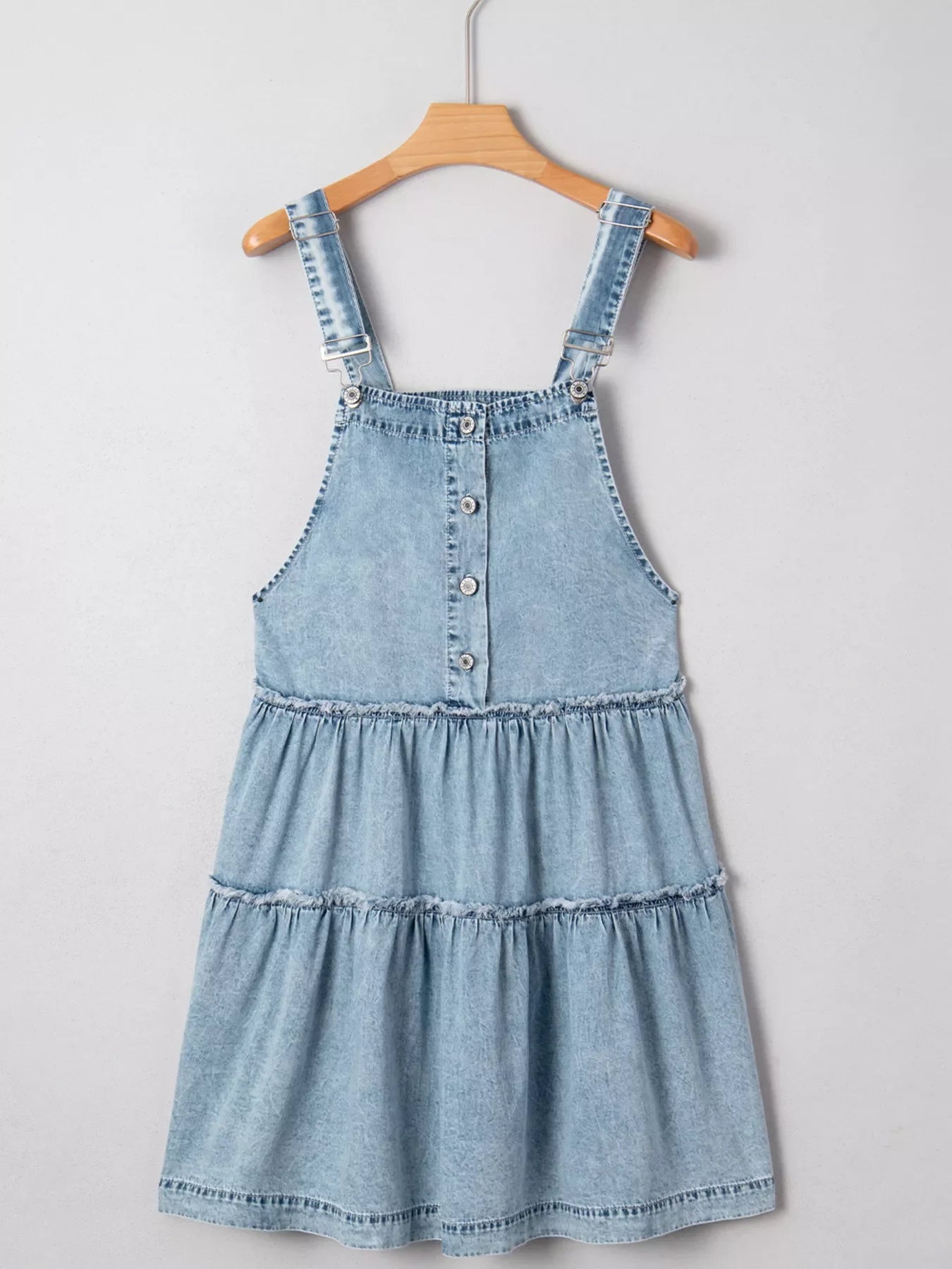 Tiered denim overall dress in light blue with button front and ruffled tiers.