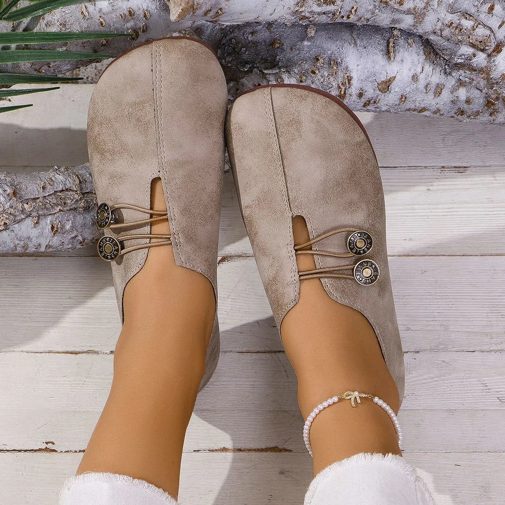 Tan leather slip-on flats with button detail and elastic lacing.