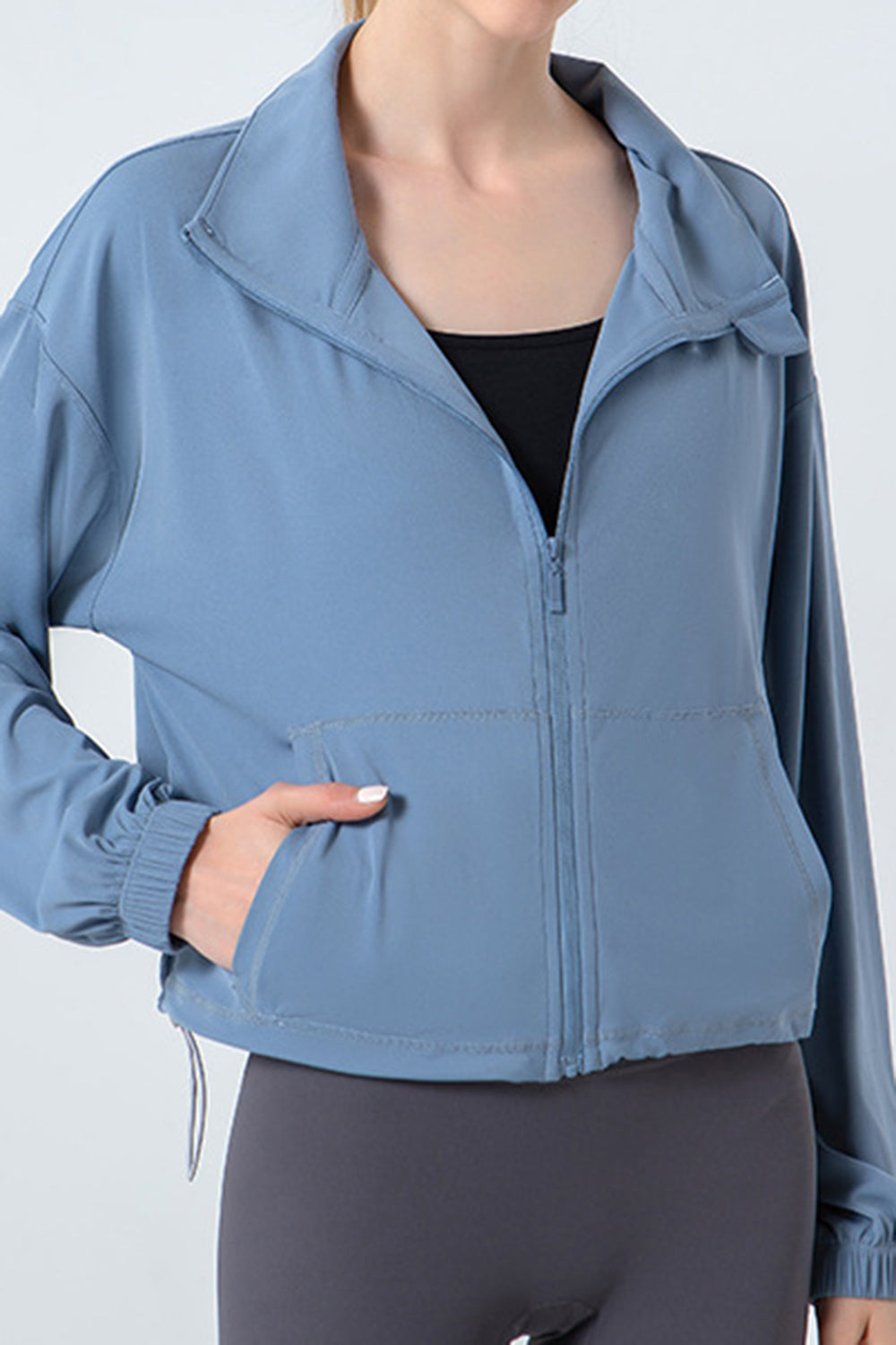 Light blue active jacket with gathered hemline, zip front, and pockets.