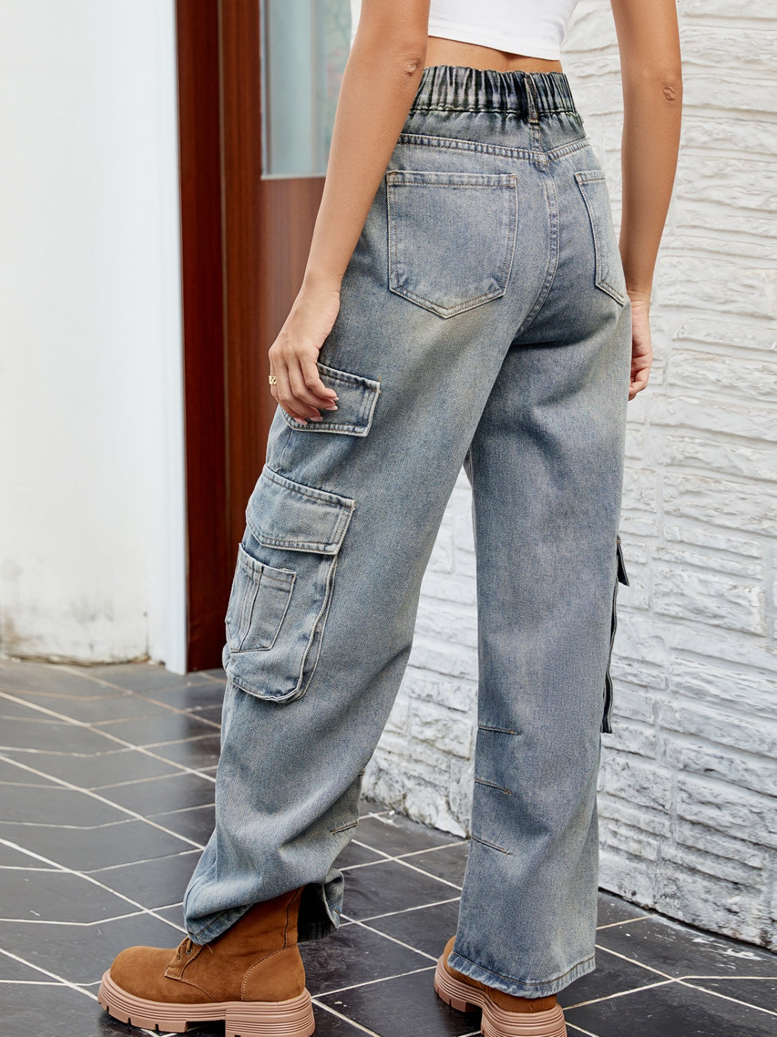 Light wash denim cargo pants with pleated waist and multiple pockets.