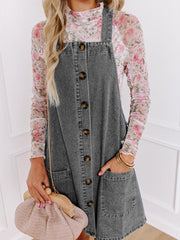 Faded gray denim pinafore dress with button front, pockets, and a floral top.