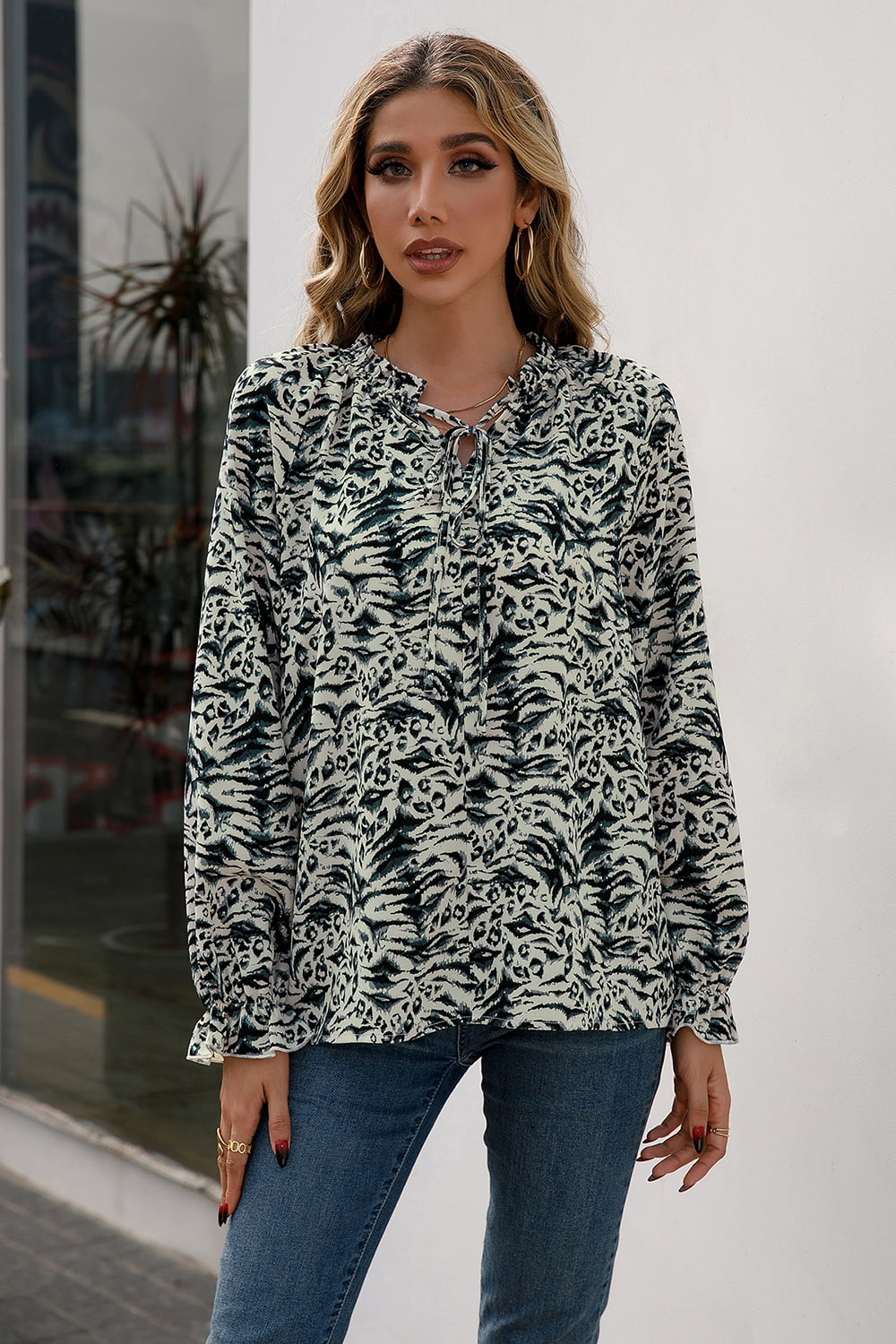 Animal print blouse with ruffle neckline and tie detail, long sleeves.