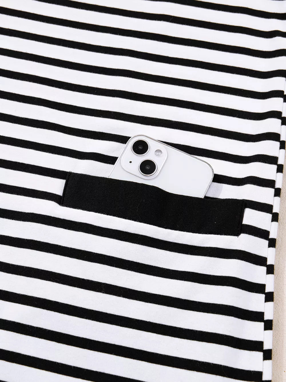 Black and white striped collared dress with button detail and functional pocket holding a phone.