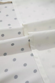 White polka dot midi dress fabric detail with tie belt visible