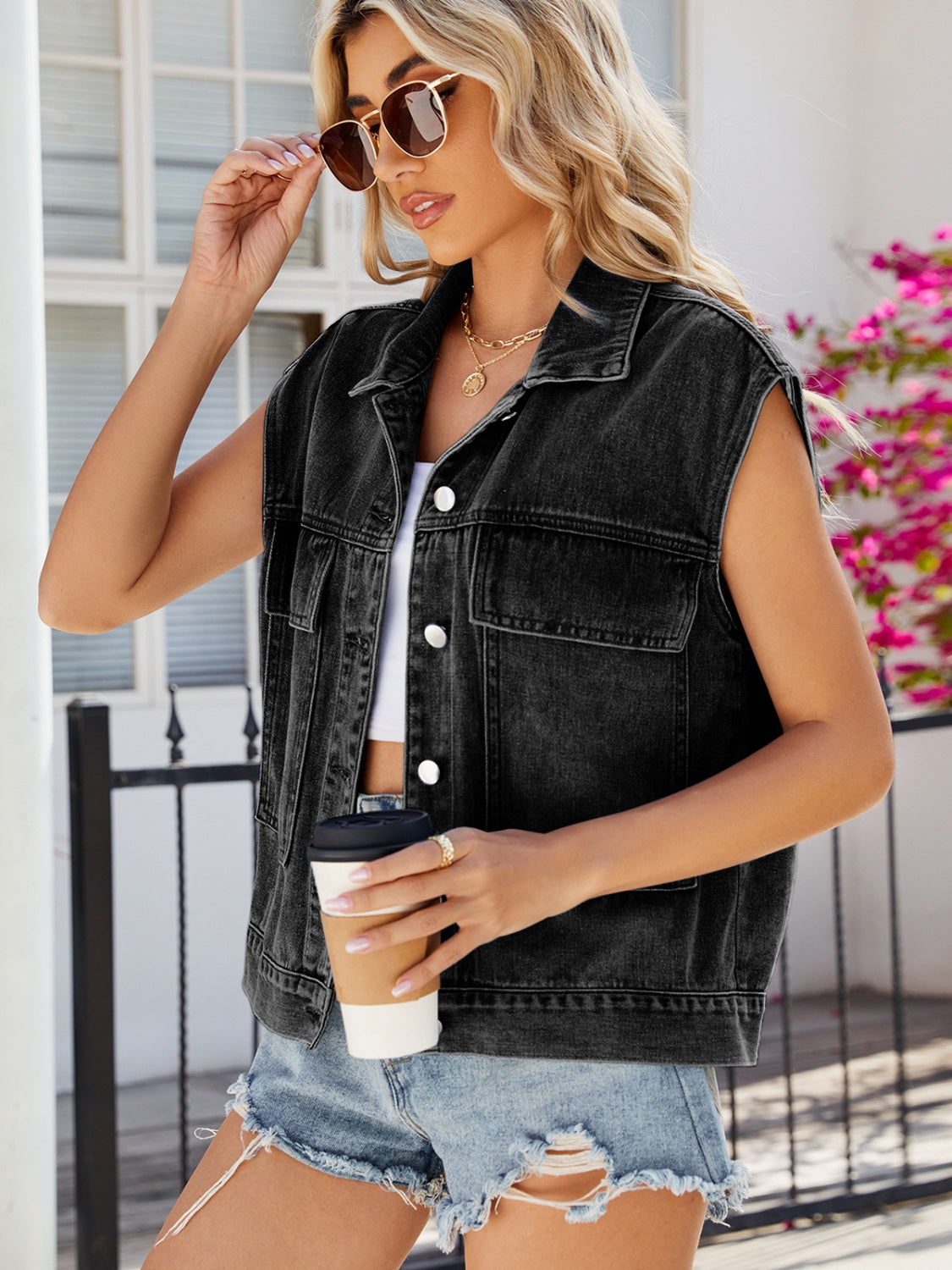 Black denim utility vest with button front and chest pockets, worn by a woman.