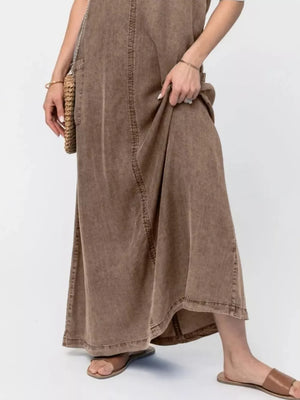 Brown washed denim maxi dress with pocket detail and a flowing skirt.