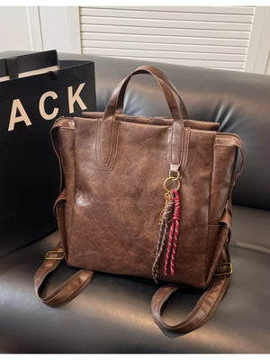 Convertible leather backpack in coffee brown with braided tassel detail and gold hardware.