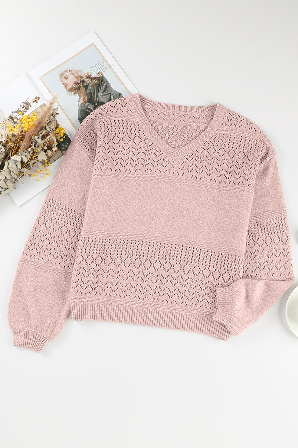 Dusty pink perforated knit v-neck pullover sweater with open knit details and ribbed cuffs.