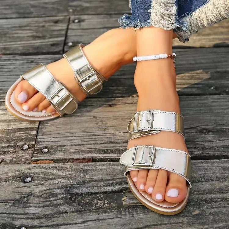 Metallic buckle slide sandals in silver with double straps and adjustable buckles.