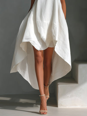 White high-low hem dress with asymmetrical flowy skirt and strappy heels.