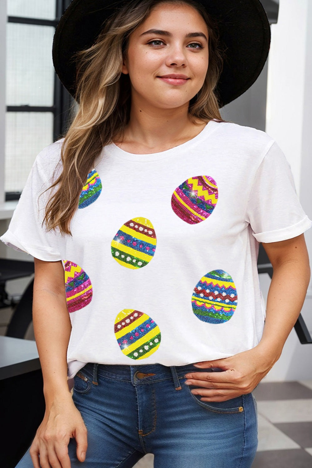 White crewneck tee with colorful sequin Easter egg appliques and rolled sleeves.