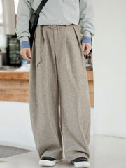 Men's wide leg trousers in beige with belt and pockets, styled with a grey sweatshirt.