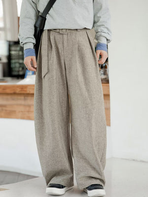 Men's wide leg trousers in beige with belt and pockets, styled with a grey sweatshirt.