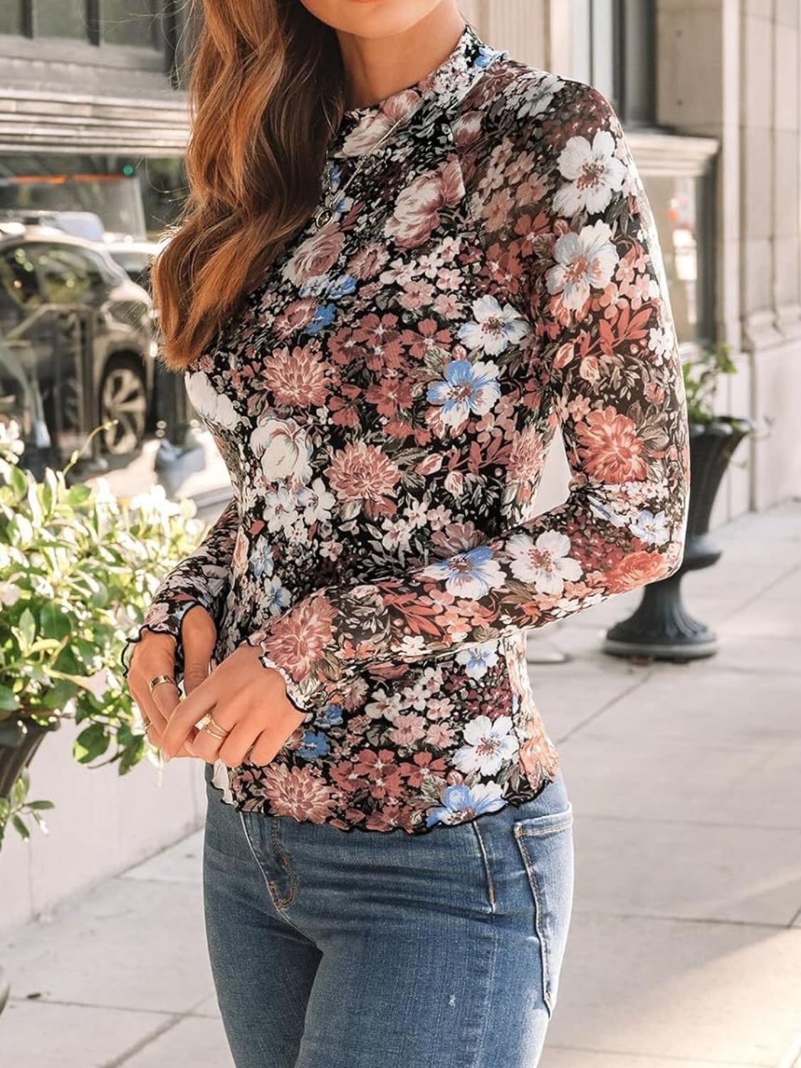 Romantic floral mesh top with mock neck and lettuce trim sleeves, styled with jeans.