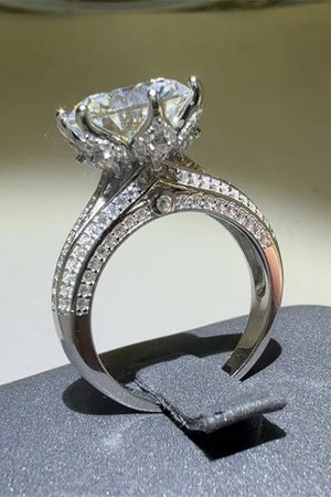 Silver moissanite ring with a large center stone and pave band.