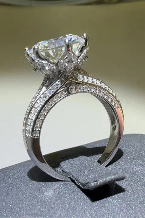 Silver moissanite ring with a large center stone and pave band.