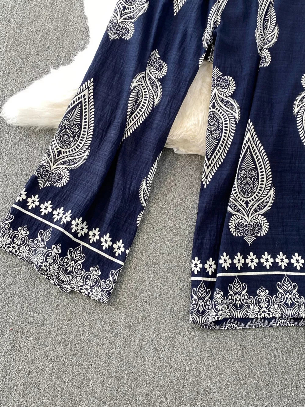Navy blue wide leg romper with white paisley print and floral trim details.