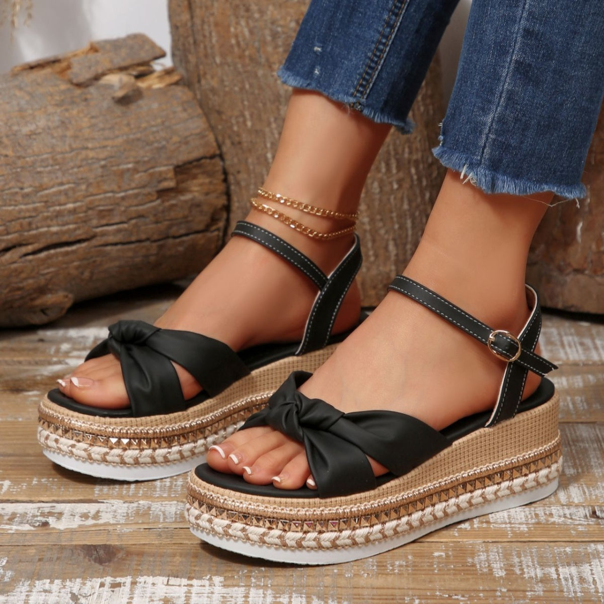 Black bow knot wedge sandals with ankle buckle and braided trim detail.