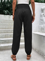 Black relaxed-fit trousers with smocked waistline and cuffed ankles.