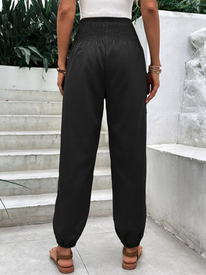 Black relaxed-fit trousers with smocked waistline and cuffed ankles.