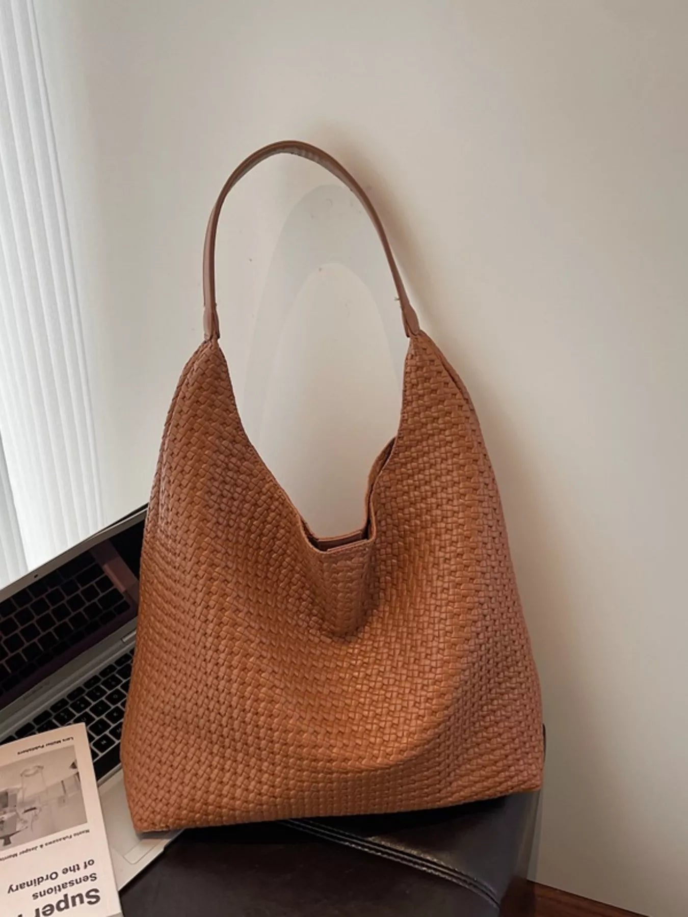 Brown woven straw tote bag with leather strap detail