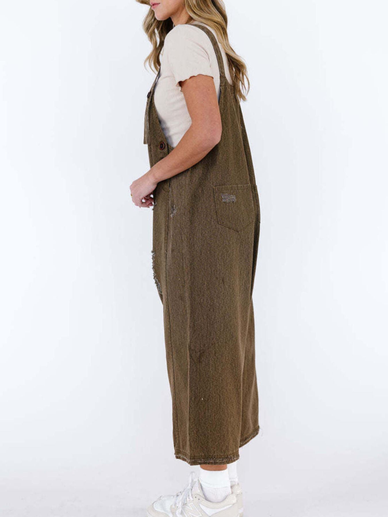 Brown relaxed fit denim overalls with ripped details and adjustable straps.