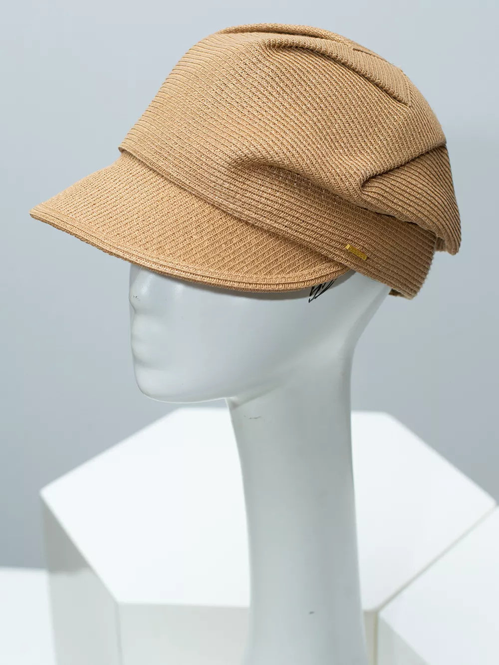Elegant woven newsboy cap in camel with a textured knit and a small gold logo detail.