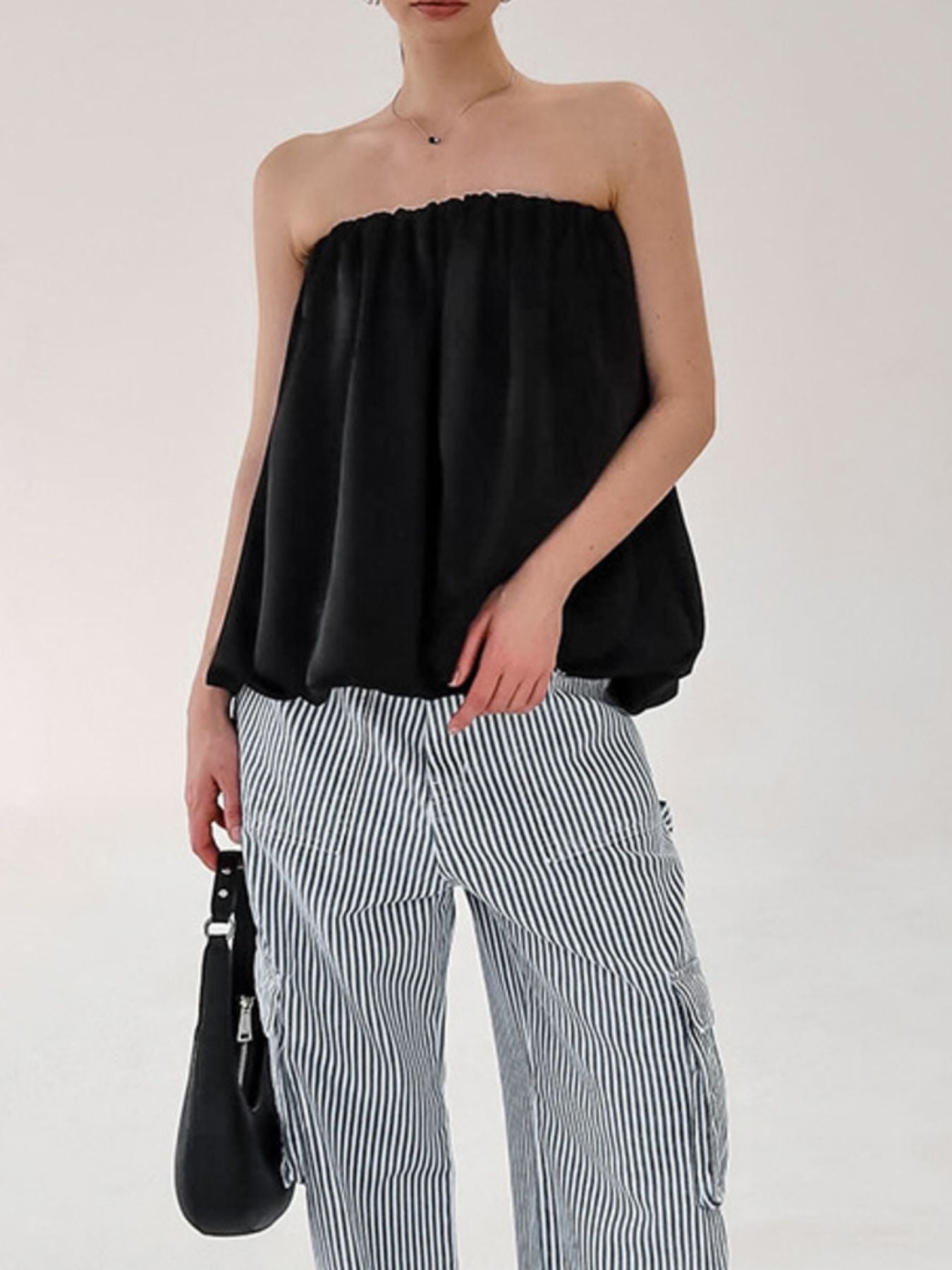 Black strapless bubble hem top with a ruffled neckline, worn with striped pants.