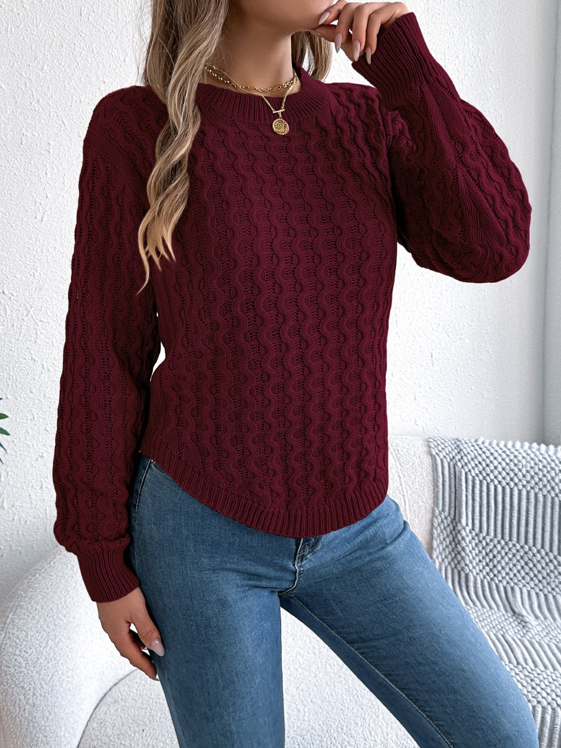 Burgundy cable knit sweater with asymmetric hem and crew neck.