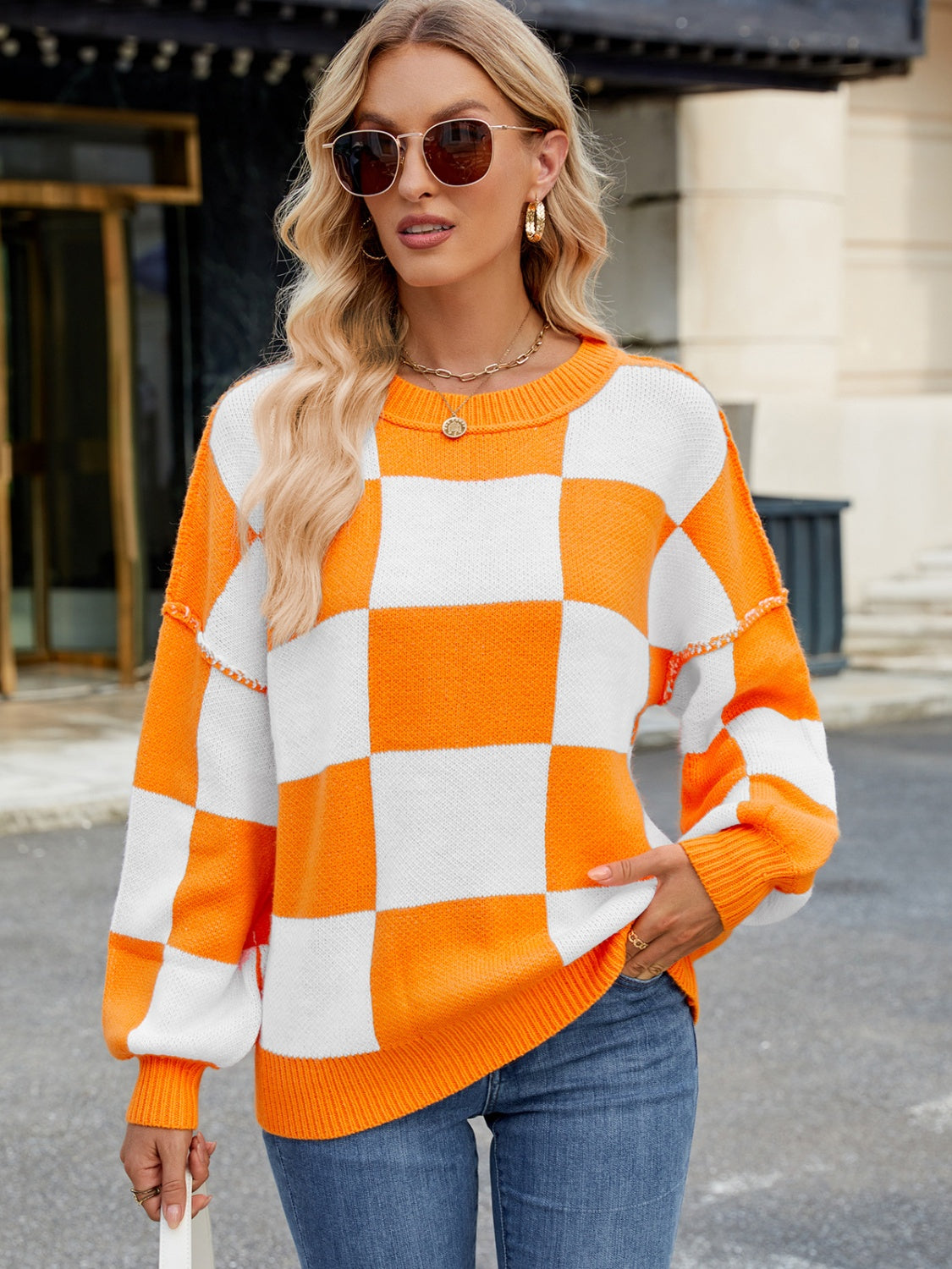 Checkerboard knit sweater in tangerine and white with balloon sleeves and crew neck.
