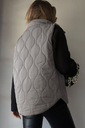 Quilted stand-collar gilet in taupe with a unique wave pattern.