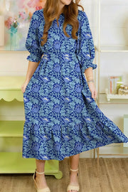 Blue floral cotton midi dress with cinched waist, frilled cuffs and tiered hem.