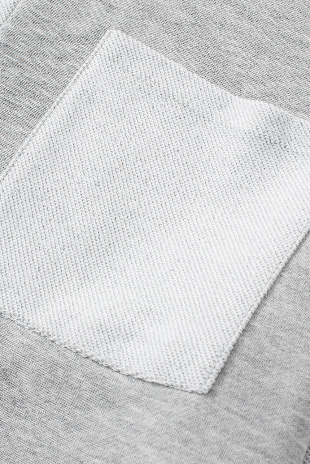 Colorblock sweatshirt in light gray with a contrasting white pocket detail.