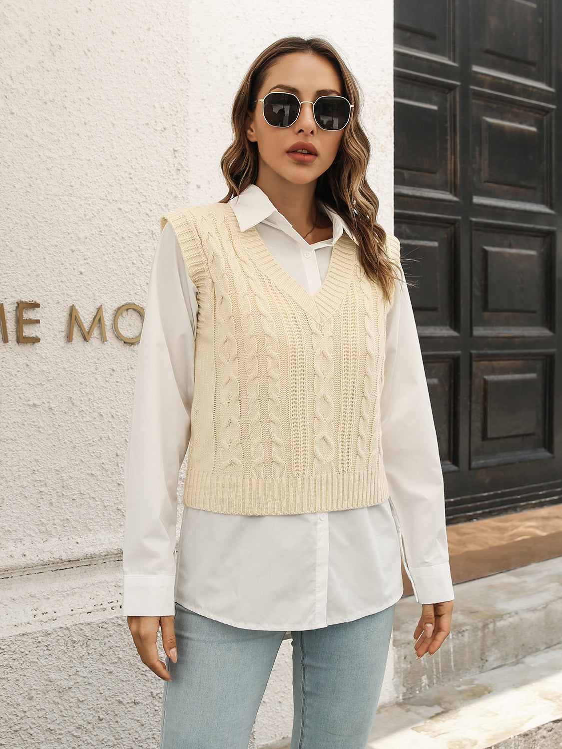 Ivory cable knit crop vest sweater with V-neck and ribbed trim, styled over a white button-down shirt.
