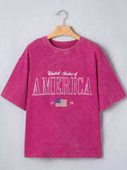 Patriotic graphic cotton t-shirt in magenta with "United States of America" text and US flag graphic.