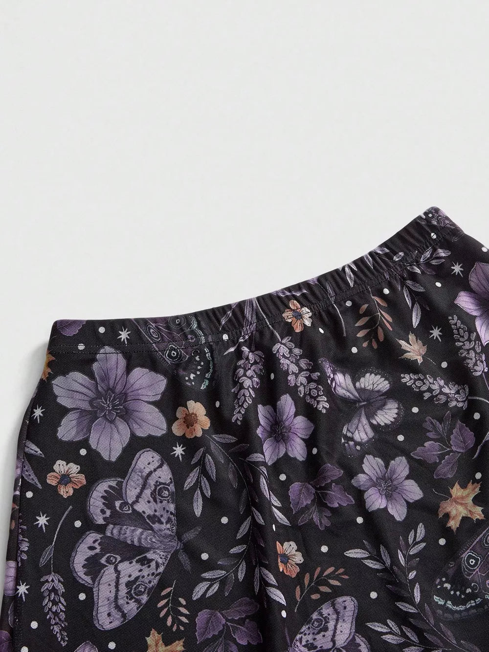 Black midi skirt with a whimsical floral and butterfly print, featuring an elastic waistband.