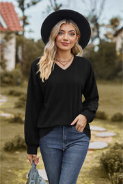 Black textured cable knit V-neck sweater with long sleeves.