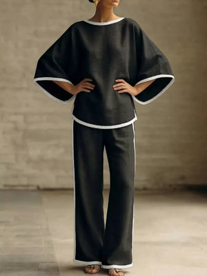 Black two-piece set with boat neck top and wide leg pants, featuring white contrast trim.