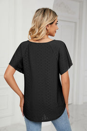Black eyelet tie-neck blouse with flutter sleeves and a curved hem.