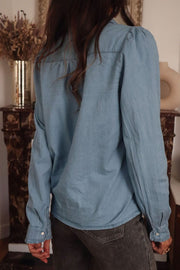 Indigo button-up blouse with puff sleeves and button cuffs.