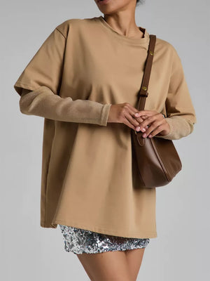 Oversized camel t-shirt with sheer glitter sleeves and a brown shoulder bag.