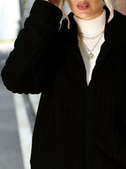 Black zip-up jacket with a plush ribbed collar, shown layered over a white turtleneck.